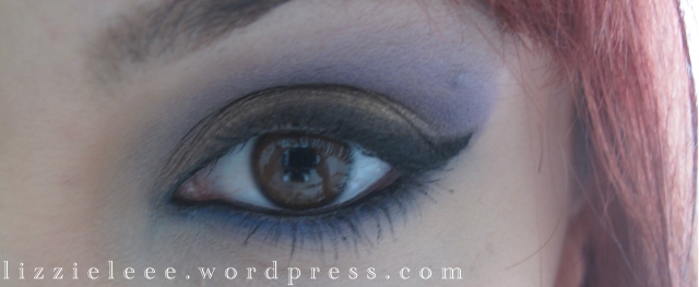 photograph of open eye showcasing gold purple and blue makeup eyeshadow look with winged liner